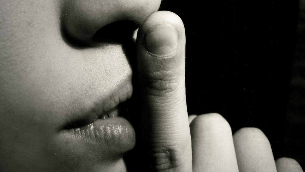 Image of a woman with a finger before her mouth, asking you to not to tell.