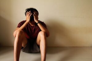 Picture of an unhappy person, sitting on the floor with his back against the wall