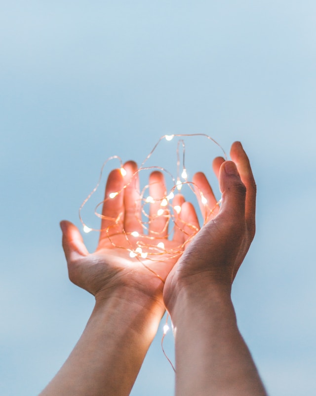 Two hands holding a string of lights.