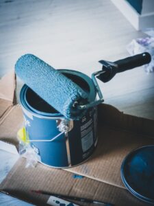 Photo of an open paint bucket with a paint roller resting on it