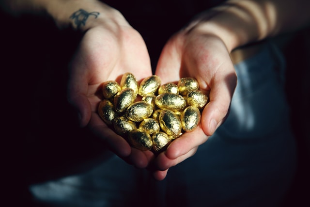 Photo of two hands holding chocolate eggs in a golden wrap
