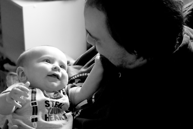 Black and white photo of a Human holding a little baby