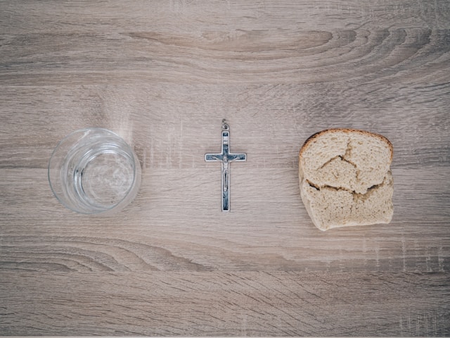Photo showing a glass of water, a piece of bread and the Holy Cross